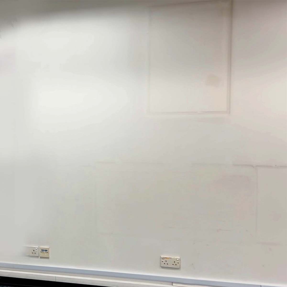 Plain white wall with electrical outlets at the bottom